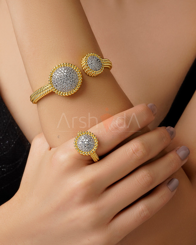 ست دستبند النگویی و انگشتر طلایی زنانه طرح دیوید یورمن با دو گوی درشت نگینکاری شده و بدنه بافتدار دانه اناری روی دست مدل.