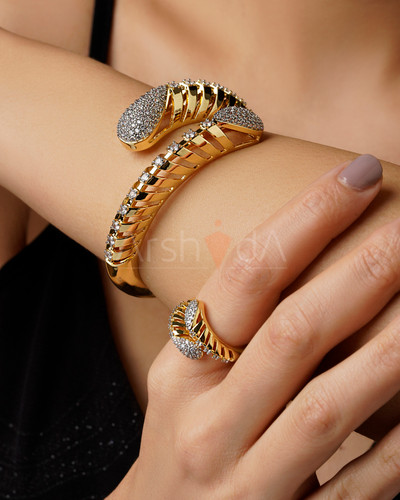 ست دستبند و انگشتر طلایی هیلیکس با طراحی مدرن مارپیچ و نگینکاری پاوهستینگ در دو انتها روی دست مدل.