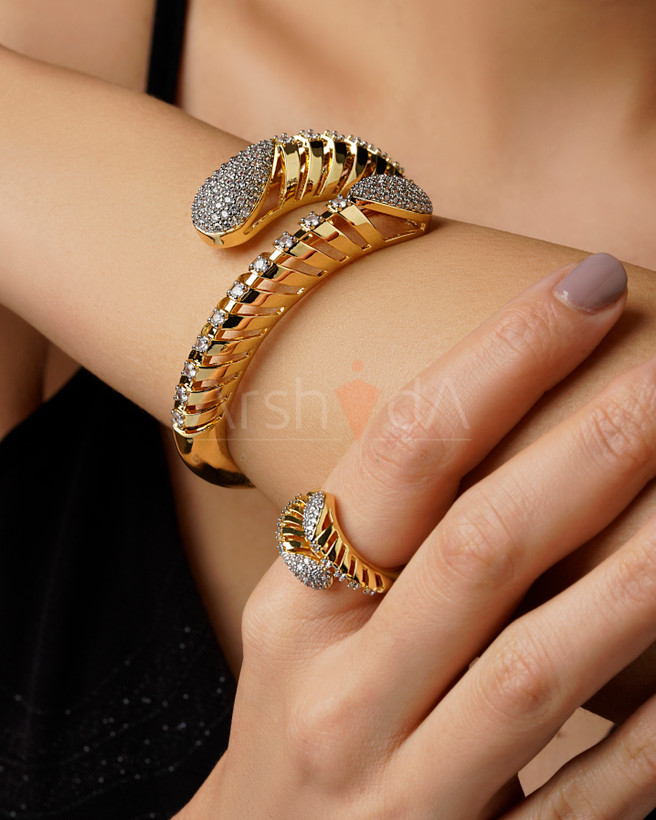 ست دستبند و انگشتر طلایی هیلیکس با طراحی مدرن مارپیچ و نگینکاری پاوهستینگ در دو انتها روی دست مدل.