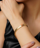 نمای نزدیک از دستبندهای لاو کارتیر رنگ طلایی و سفید با بافت خطی و نماد پیچ کارتیر بر روی دست مدل.