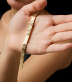 نمای نزدیک از دستبندهای لاو کارتیر رنگ طلایی و سفید با بافت خطی و نماد پیچ کارتیر بر روی دست مدل.