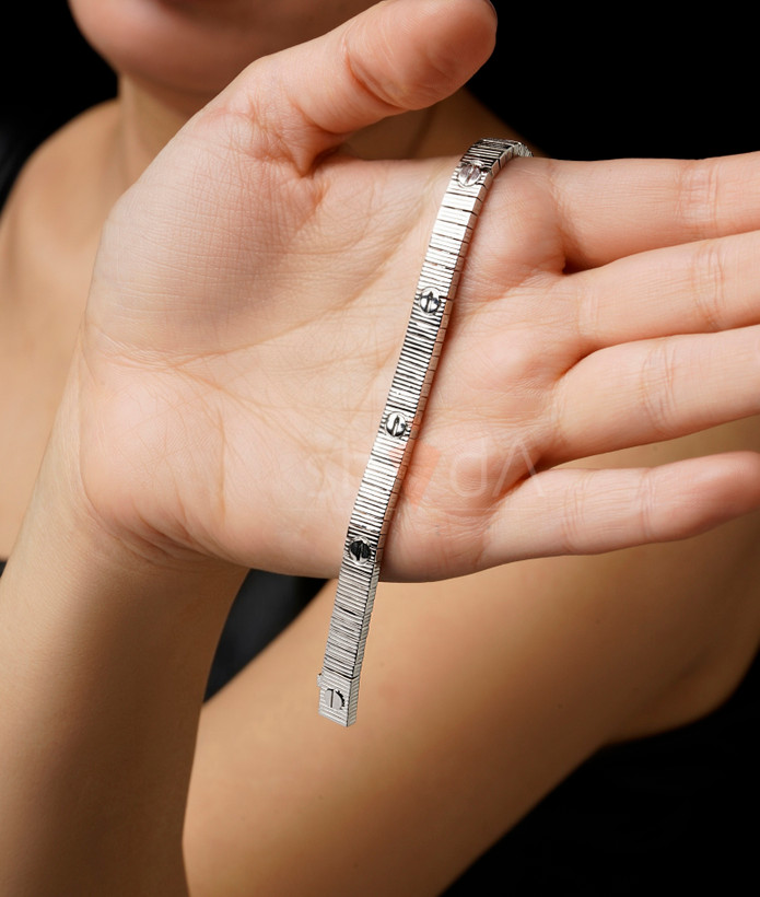 نمای نزدیک از دستبندهای لاو کارتیر رنگ طلایی و سفید با بافت خطی و نماد پیچ کارتیر بر روی دست مدل.