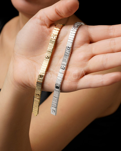 نمای نزدیک از دستبندهای لاو کارتیر رنگ طلایی و سفید با بافت خطی و نماد پیچ کارتیر بر روی دست مدل.