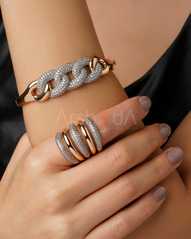 ست لوکس بنگل و انگشتر طلایی پورتوفینو با طرح پیوندهای زنجیرهای و نگینکاری پاوهستینگ روی دست مدل.