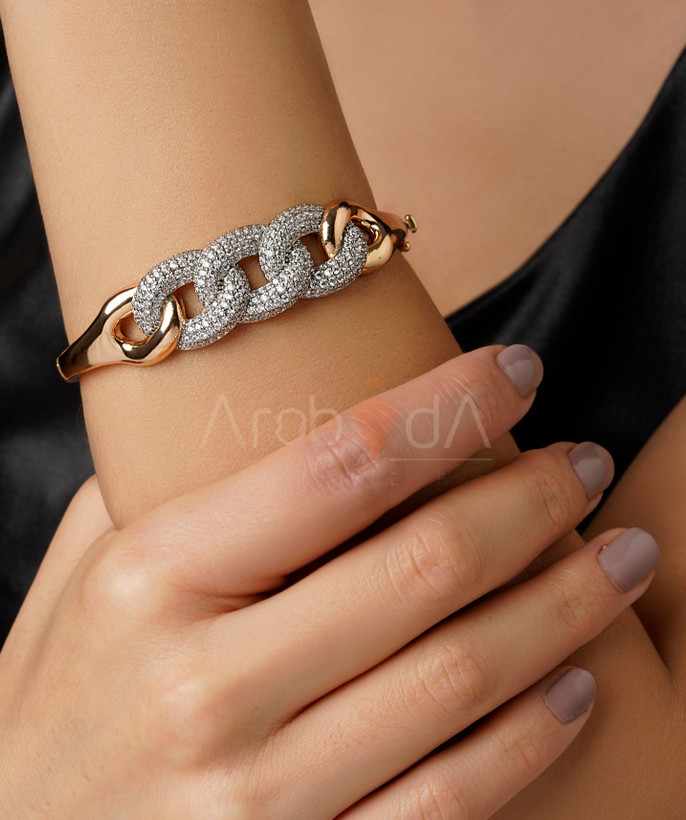 ست لوکس بنگل و انگشتر طلایی پورتوفینو با طرح پیوندهای زنجیرهای و نگینکاری پاوهستینگ روی دست مدل.