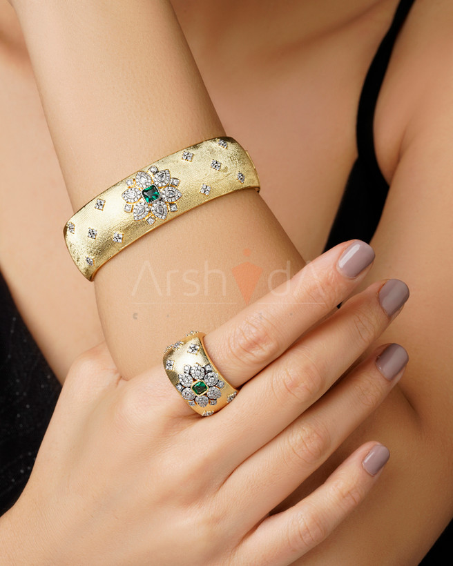ست لوکس بنگل و انگشتر طلایی برند بوچلاتی با بافت ریگاتو، گلبرگهای رادیومکاری شده و نگین زمردی مرکزی روی دست مدل.