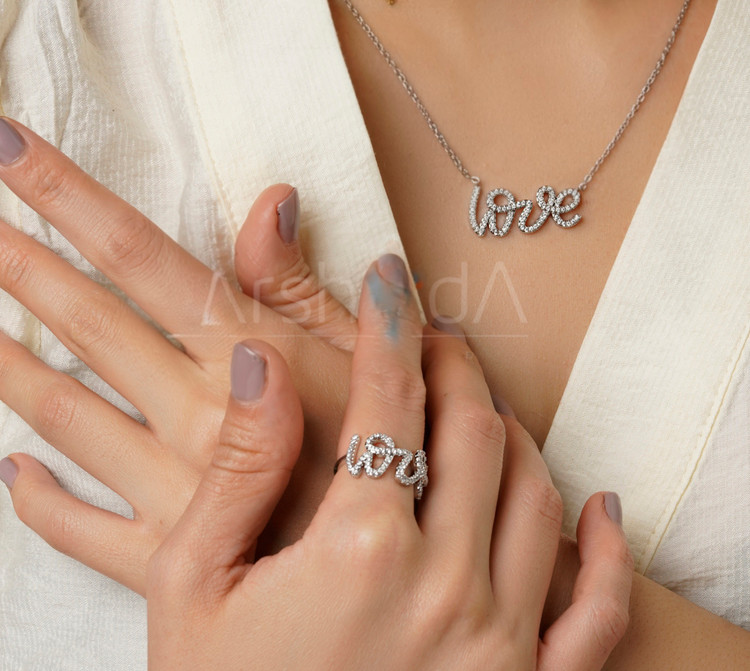 ست گردنبند و انگشتر طلایی و نقرهای طرح نوشته لاو تمام نگین با مخراجکاری درخشان زیرکونیوم و آبکاری طلا روی دست و گردن مدل در آرشیدا گالری.