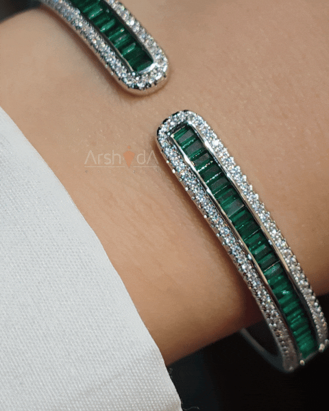 دستبند النگویی باز طرح طلا در دو رنگ پایه طلایی و نقرهای، تزئین شده با ردیف نگینهای مستطیلی رنگی و حاشیه زیرکونیوم در رنگهای سبز، آبی، صورتی و سفید.